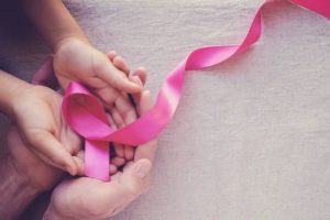 A pink breast cancer ribbon in a hand