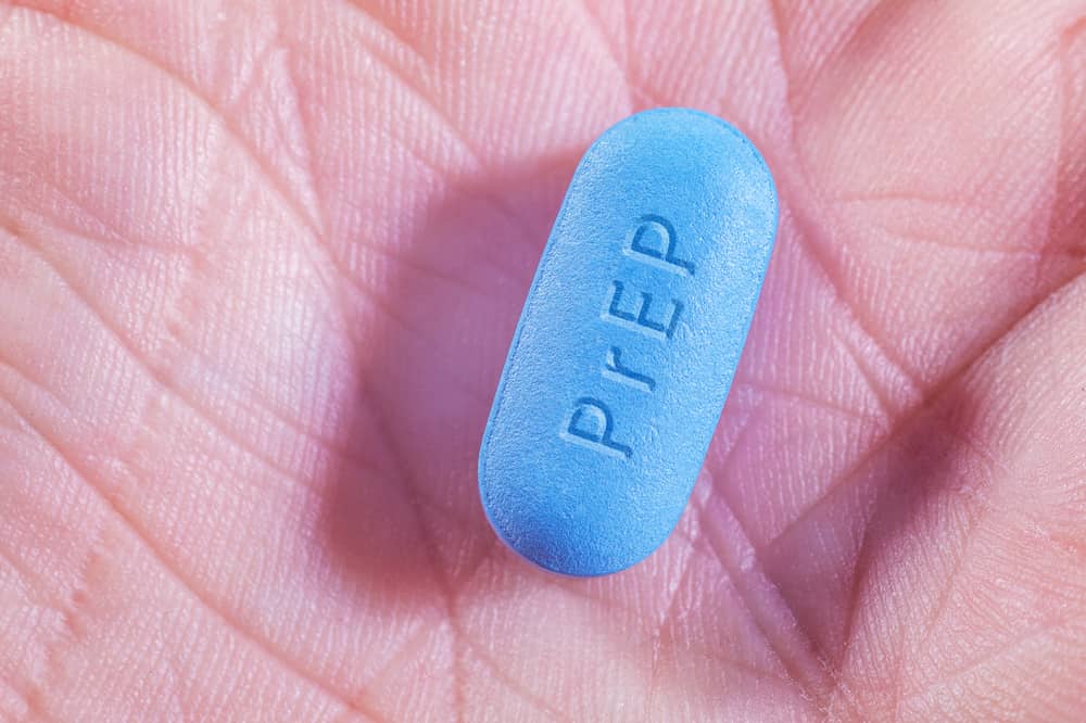 A patient holds a blue Truvada pill in their palm